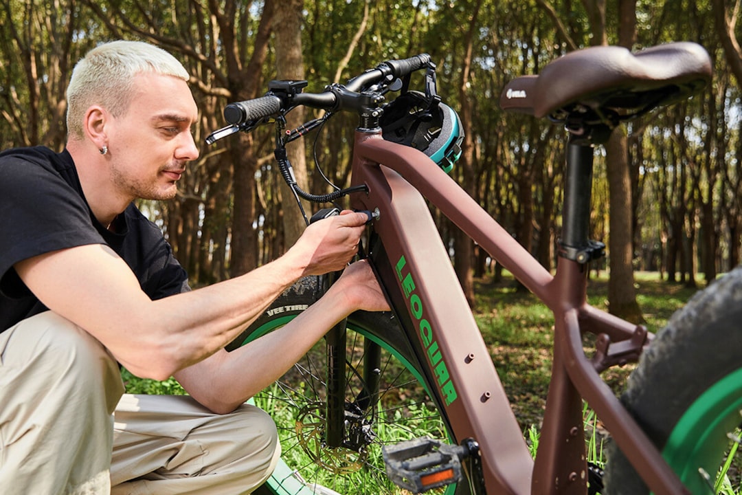 A man fixing a bike in the woods